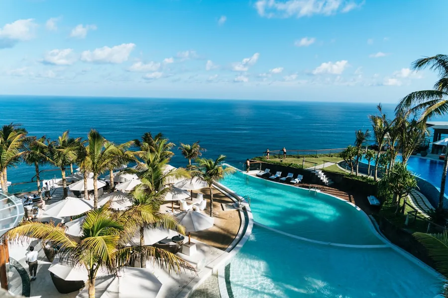 An infinity pool framed by palm trees overlooking the ocean at a luxury all-inclusive resort